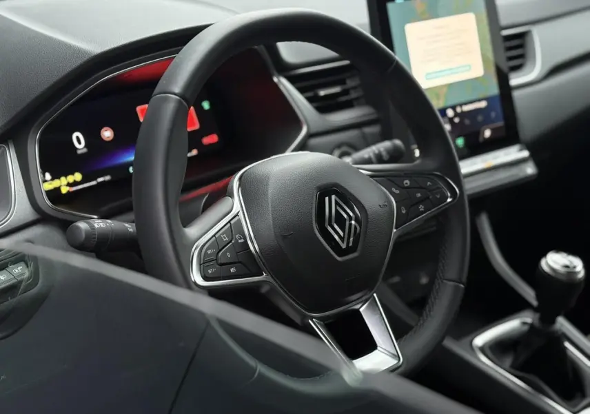 Vue intérieure centrée sur le volant noir du Renault Captur 2025 avec tableau de bord numérique et écran tactile vertical.