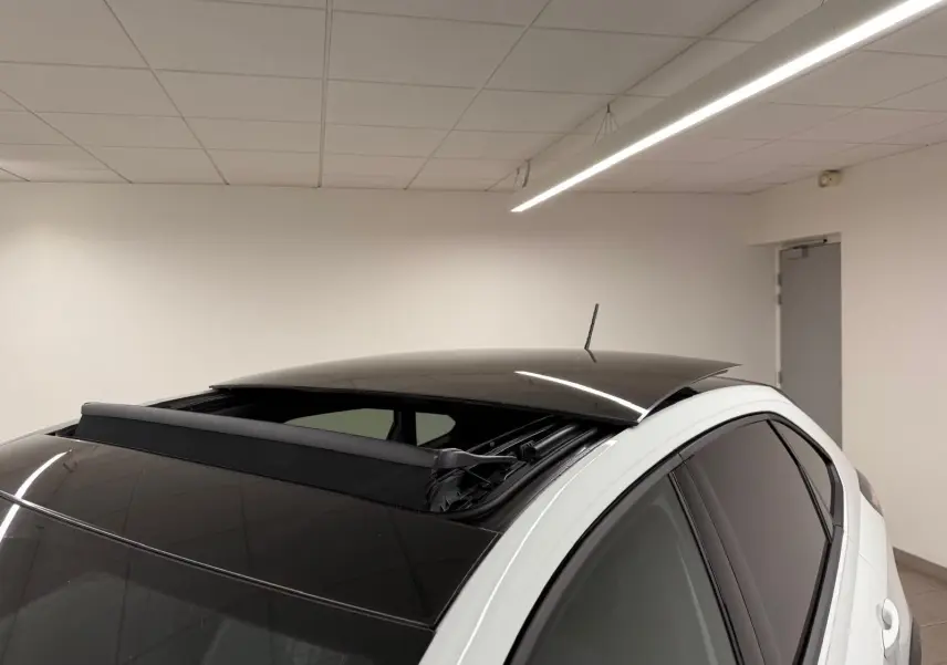 Vue 3/4 arrière droite d'un Volkswagen Taigo blanc pur avec toit ouvrant électrique noir partiellement ouvert.