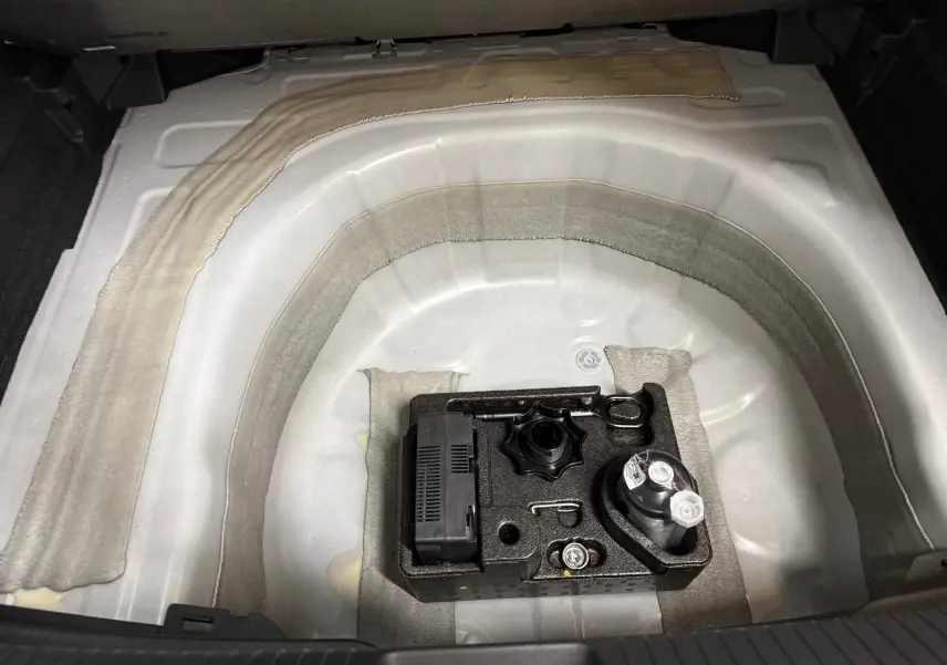 Vue plongeante sur le coffre de la Volkswagen Taigo 2025, montrant le rangement sous plancher avec kit de dépannage.