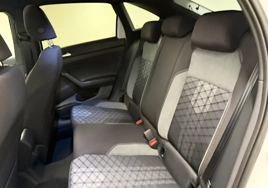 Vue intérieure côté gauche montrant la banquette arrière en tissu gris et noir avec motifs géométriques du Volkswagen Taigo 2025.