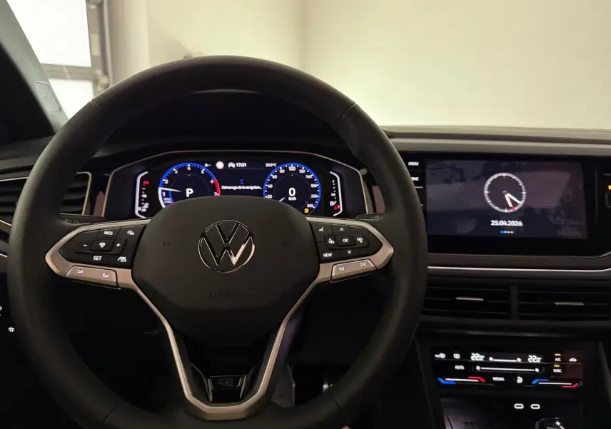 Vue intérieure centrée sur le volant multifonctions Volkswagen avec tableau de bord digital et écran tactile noir.