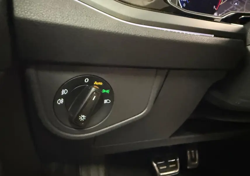 Gros plan sur le bouton de commande des phares du Volkswagen Taigo 2025, intérieur noir avec éclairage LED.