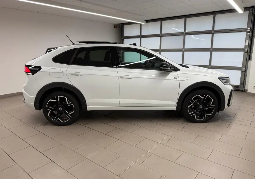 Vue latérale droite d'un Volkswagen Taigo blanc pur avec toit noir, jantes alliage noires et badge R-Line visible.