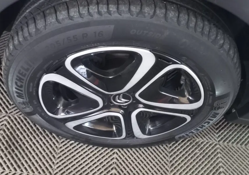 Gros plan sur la roue avant droite d'une Citroën C3 noire 2024 avec jante alliage noire et argentée au design moderne.