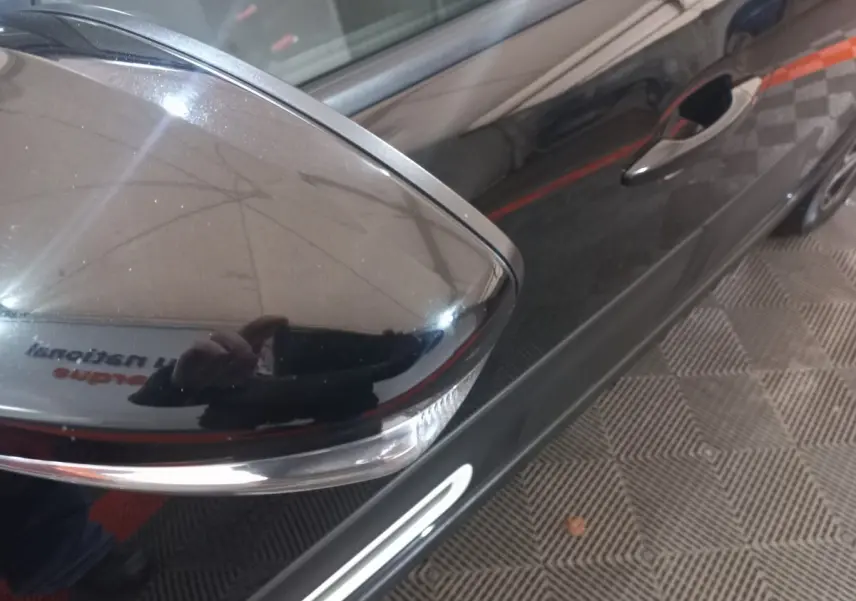 Gros plan sur le rétroviseur droit noir brillant de la Citroën C3 2024, avec reflet du photographe sur la porte.