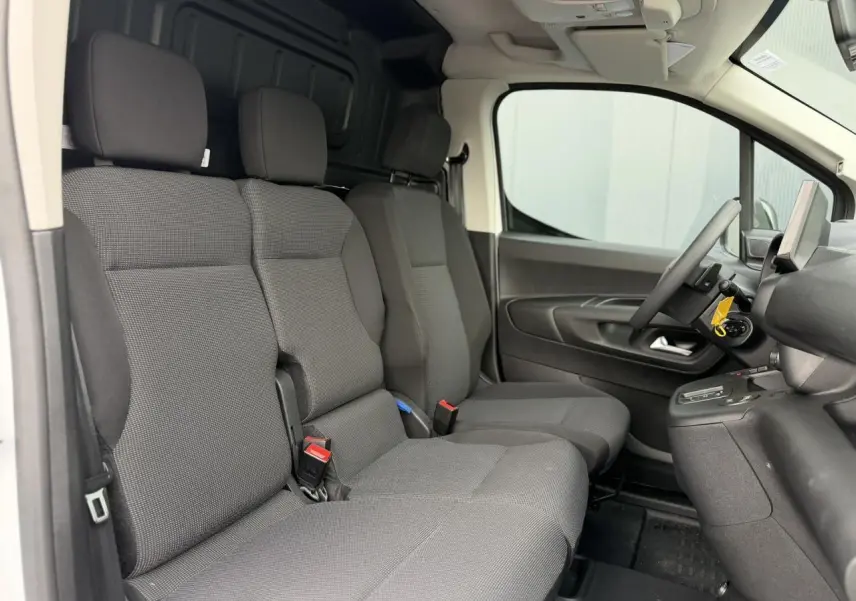 Vue intérieure côté conducteur du Citroën Berlingo Van XL 2026, sièges tissu gris et plancher bois visible.