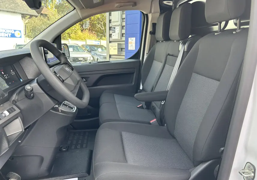 Vue intérieure côté conducteur du Citroën Jumpy Fourgon blanc 2025, sièges tissu gris et tableau de bord moderne.