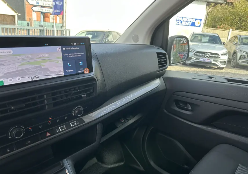 Vue intérieure côté passager du tableau de bord du Citroën Jumpy Fourgon blanc avec écran tactile et commandes climatisation visibles.