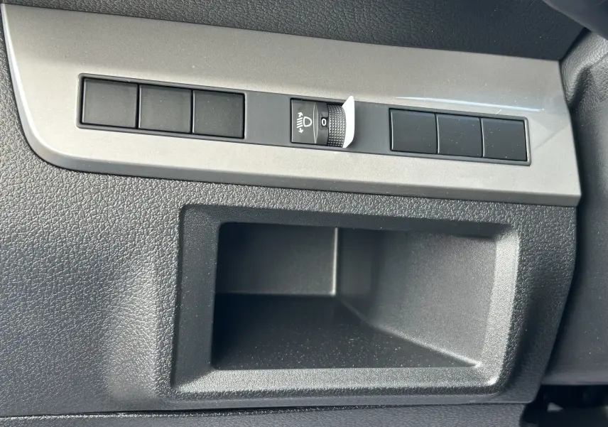 Gros plan sur le tableau de bord noir du Citroën Jumpy Fourgon blanc, avec commande de réglage des phares et rangement intégré.