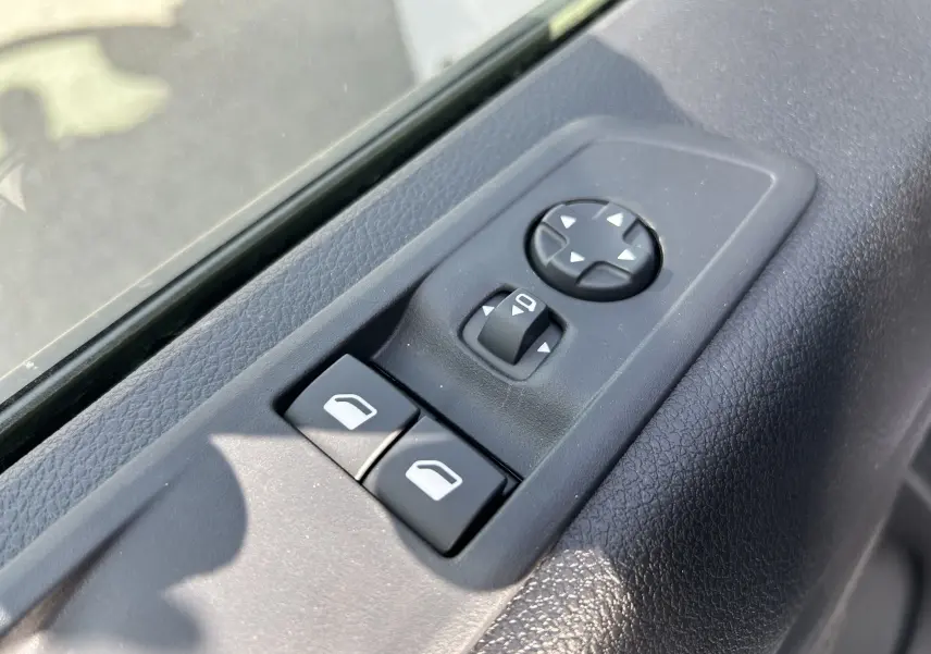 Gros plan sur les commandes de réglage des rétroviseurs et des vitres côté conducteur du Citroën Jumpy Fourgon blanc 2025.