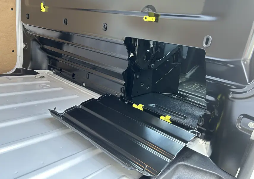 Détail intérieur du plancher blanc du Citroën Jumpy Fourgon 2025 avec trappe d'accès noire ouverte et fixations jaunes visibles.