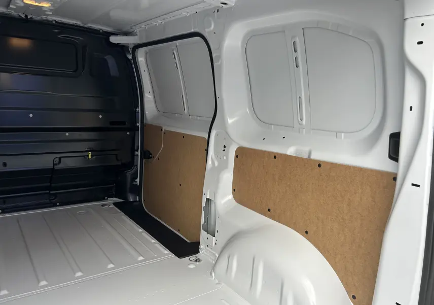 Intérieur du fourgon Citroën Jumpy blanc, vue latérale droite montrant la cloison et les panneaux de protection en bois.