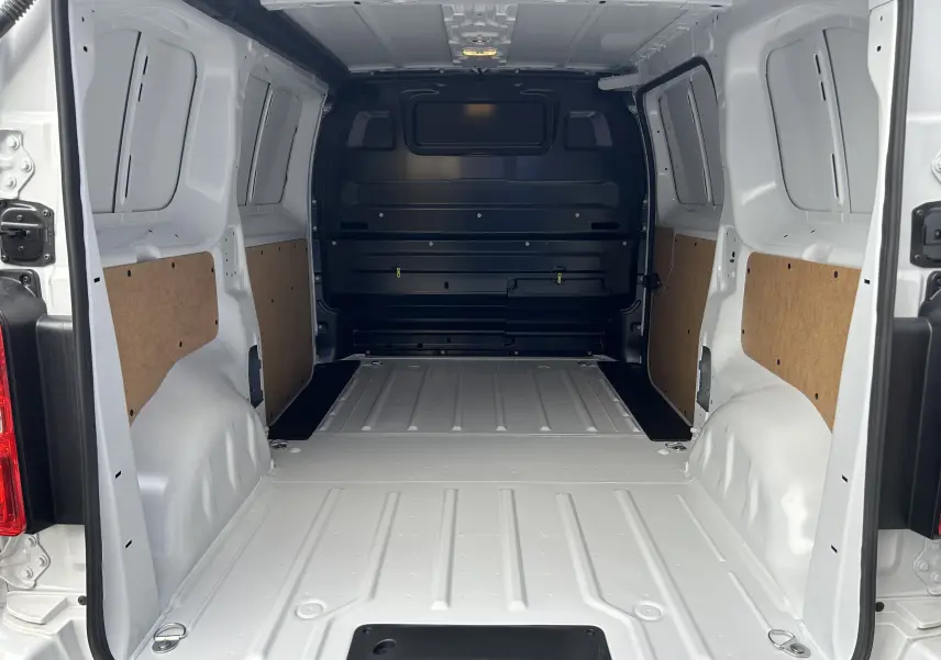 Intérieur du fourgon Citroën Jumpy blanc vu de l'arrière, montrant l'espace de chargement vide avec panneaux latéraux en bois.