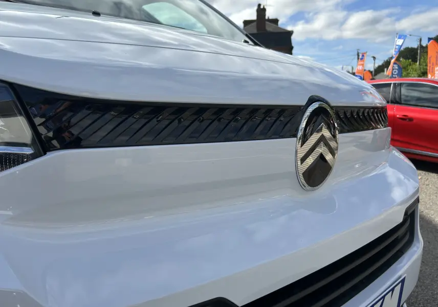 Gros plan sur la calandre avant blanche du Citroën Jumpy Fourgon 2025 avec logo chromé et détails noirs brillants.