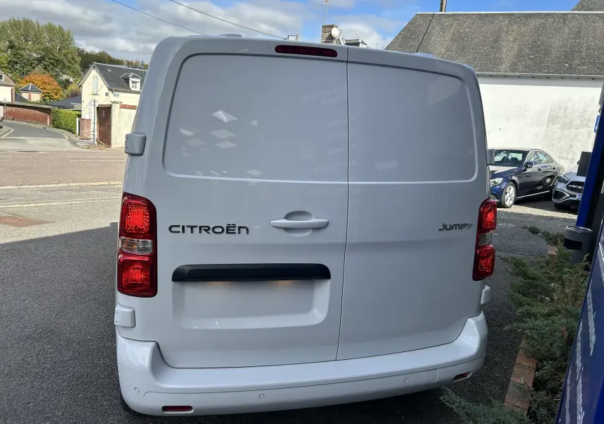 Vue arrière d'un utilitaire blanc Citroën Jumpy Fourgon avec feux rouges et poignées centrales visibles.