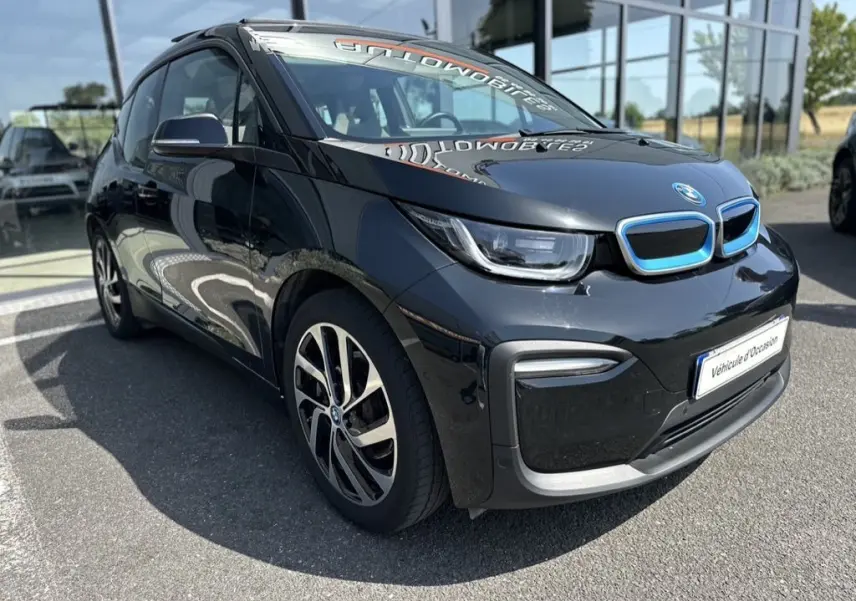 BMW i3 noire électrique vue en 3/4 avant droit, avec calandre bleutée et jantes distinctives en alliage.