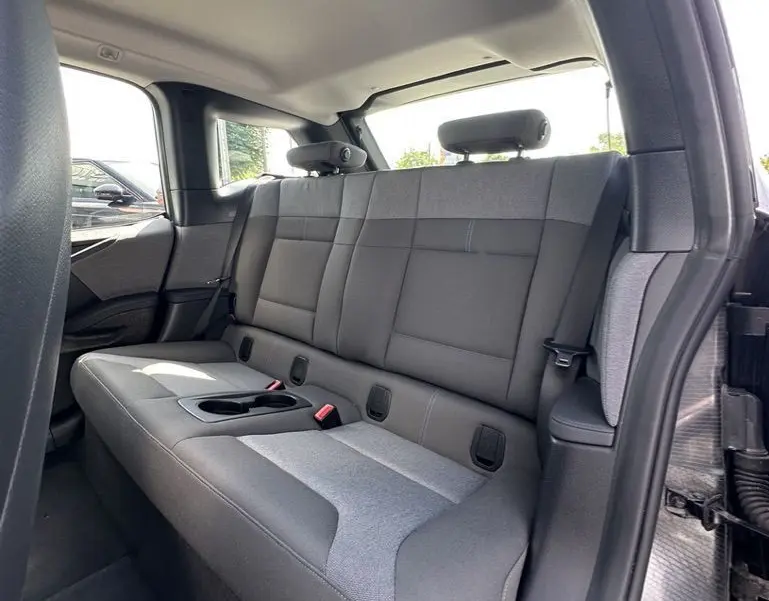 Vue intérieure côté droit des sièges arrière gris clair et foncé d'une BMW i3 noire électrique 2022 avec porte ouverte.