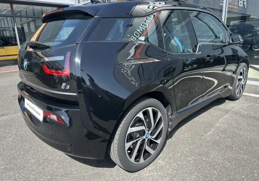 Vue 3/4 arrière côté gauche d'une BMW I3 noire électrique 2022 avec jantes distinctives et vitres teintées.