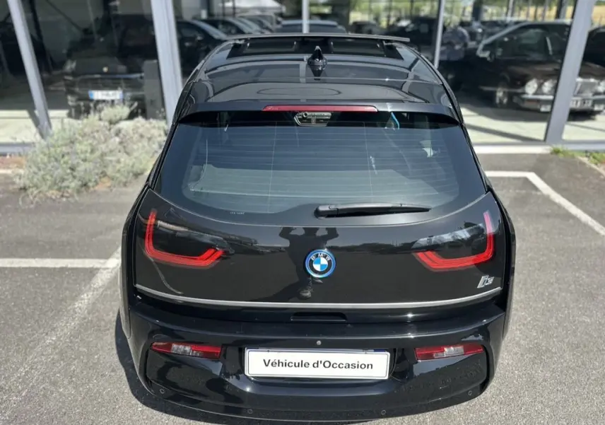 Vue arrière d'une BMW i3 noire 2022 avec feux LED distinctifs et logo centré, stationnée devant un showroom.