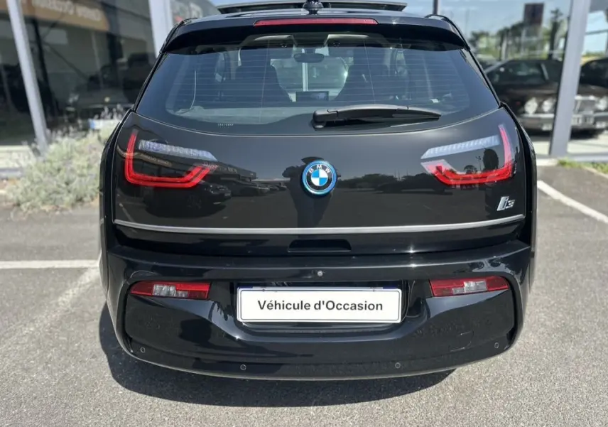 Vue arrière d'une BMW i3 noire électrique 2022 avec feux LED distinctifs et logo central sur un parking.