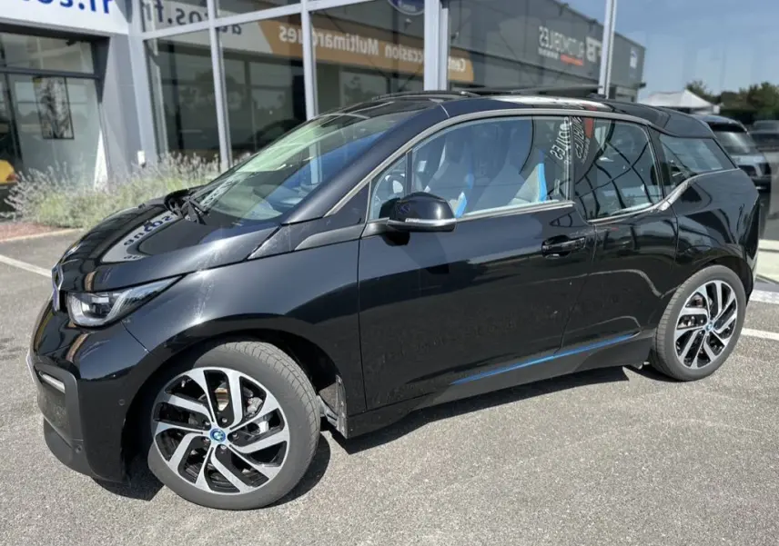BMW i3 noire vue de profil côté gauche, mettant en valeur ses jantes distinctives et son design compact électrique.