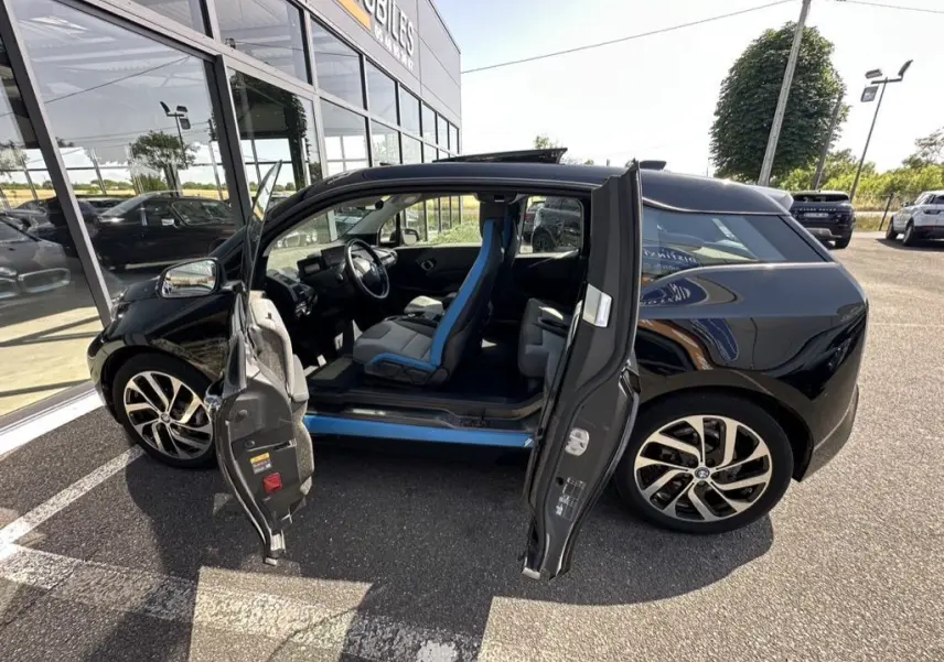 BMW i3 noire 2022 vue de profil droit avec portes ouvertes dévoilant l'intérieur aux sièges bleu et noir.