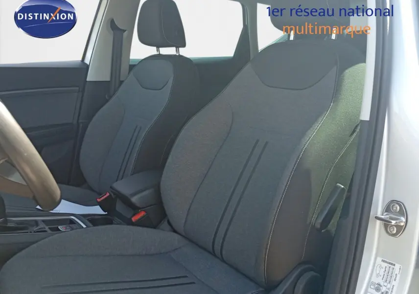 Intérieur du SEAT Ateca 2023 en vue côté gauche, montrant les sièges en tissu gris et la portière argentée ouverte.