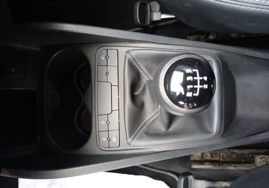 Vue plongeante sur le levier de vitesse manuel noir et la console centrale grise de la SEAT Ibiza ST rouge de 2015.