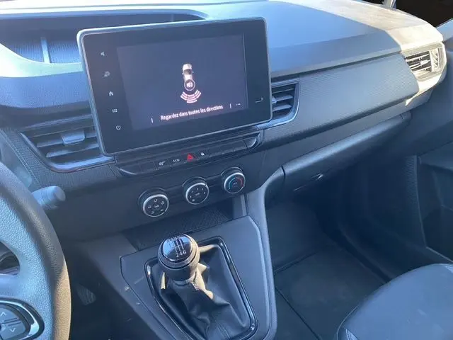 Vue intérieure du tableau de bord et levier de vitesse manuel du Renault Kangoo Van TCe 100 blanc, avec écran tactile et commandes climatiques.