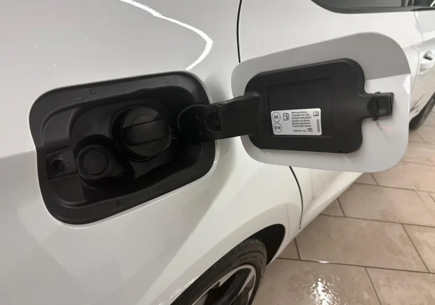 Ouverture de la trappe à carburant côté gauche d'une CUPRA Leon blanc Nevada, vue rapprochée sur la carrosserie et la roue arrière.