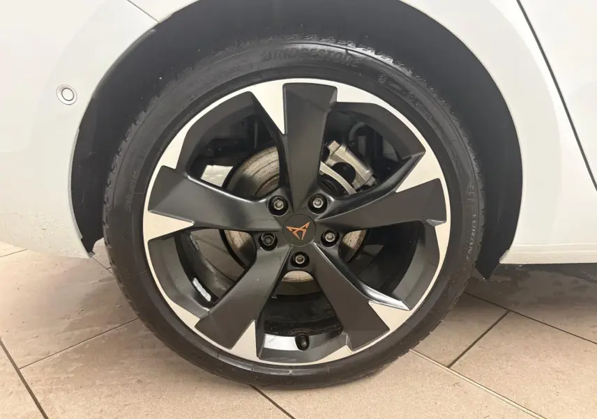 Gros plan sur la roue avant gauche de la CUPRA Leon blanche Nevada, avec jante noire et argent au design moderne.