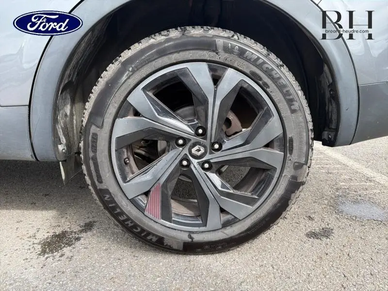 Gros plan sur la roue avant droite gris métallisé d’un Renault Arkana 2023 avec jante alu noire et logo Renault central.