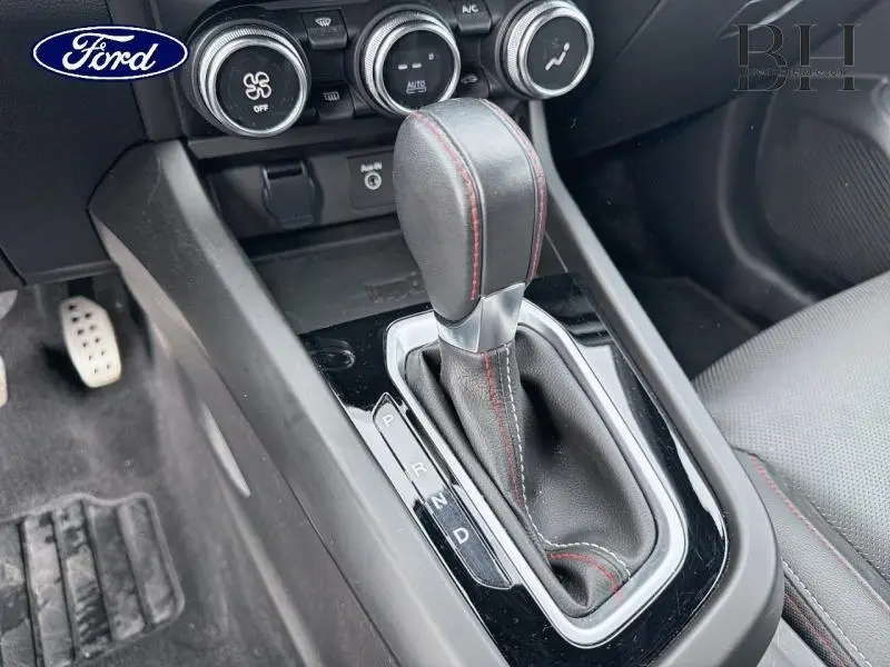 Gros plan sur la console centrale et levier de vitesse cuir noir avec surpiqûres rouges dans l'habitacle Renault Arkana gris.