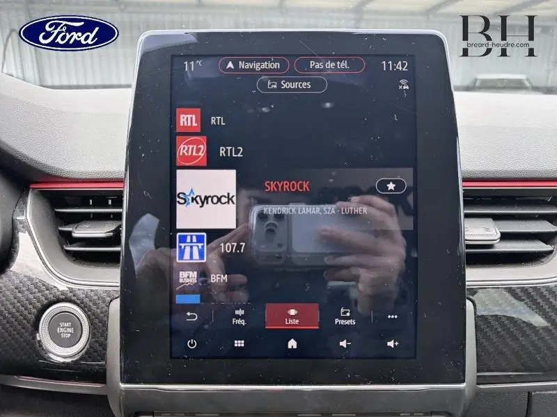 Écran tactile central du tableau de bord d’une Renault Arkana gris métallisé, affichant les radios disponibles.
