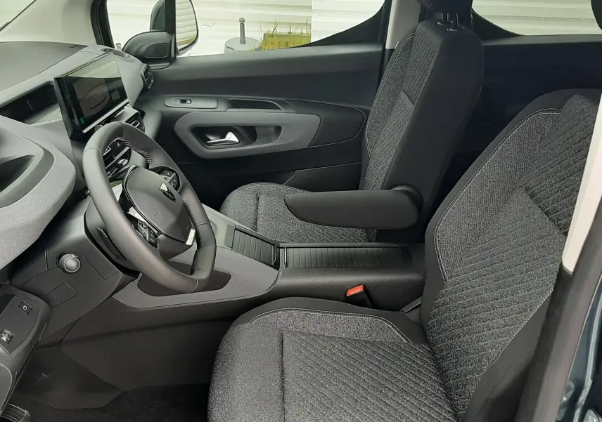 Vue intérieure côté conducteur du Peugeot Rifter 2026 bleu Kiama, avec sièges tissu gris et tableau de bord moderne.