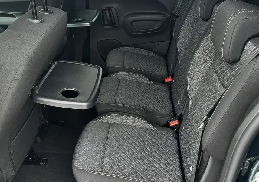 Vue latérale intérieure des sièges arrière gris tissu du Peugeot Rifter 2026, avec tablette rabattable côté gauche.