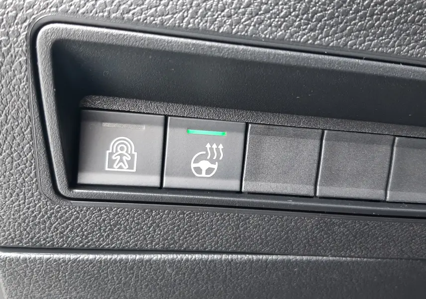 Gros plan sur les boutons de commande du tableau de bord du Peugeot Rifter 2026, plastique noir texturé.