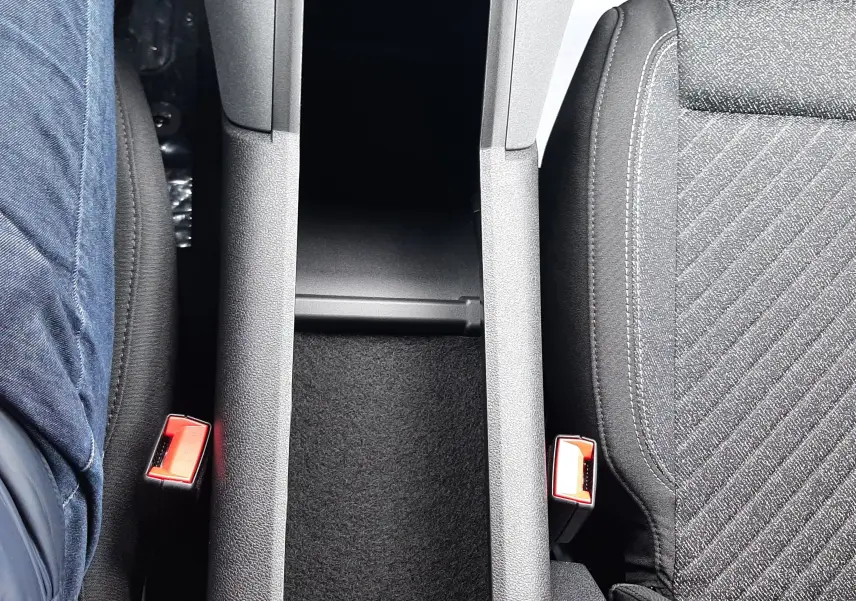 Vue plongeante sur la console centrale et les sièges avant en tissu gris du Peugeot Rifter 2026, intérieur sobre.