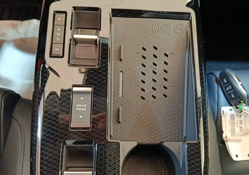 Vue plongeante sur la console centrale noire brillante du Citroën C5 Hybride 145ch avec commandes et porte-gobelet.