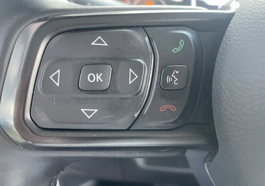 Gros plan sur les commandes multifonctions noires du volant du Jeep Wrangler blanc 2018, boutons directionnels et appels.