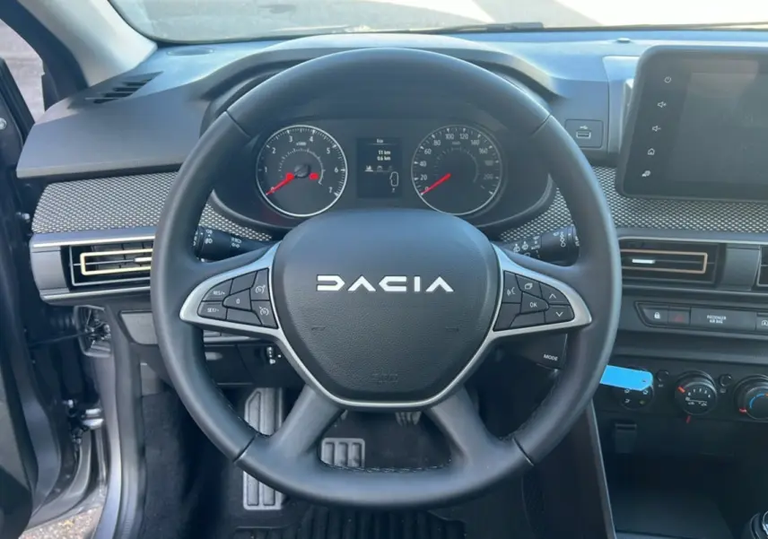 Vue intérieure centrée sur le volant DACIA d'une Sandero Stepway 2025, avec tableau de bord et commandes visibles.
