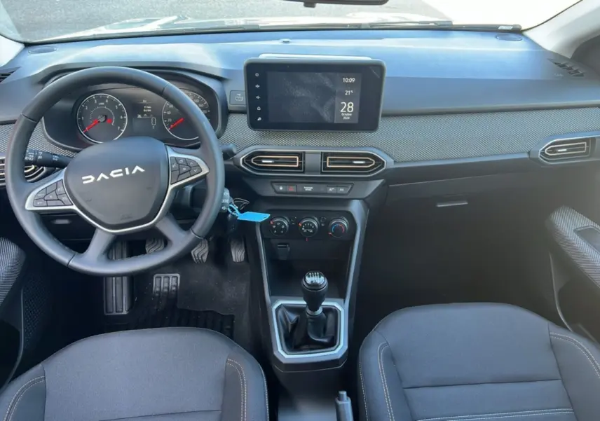 Intérieur de la Dacia Sandero Stepway 2025, vue du tableau de bord avec volant, écran tactile et levier de vitesses manuel.