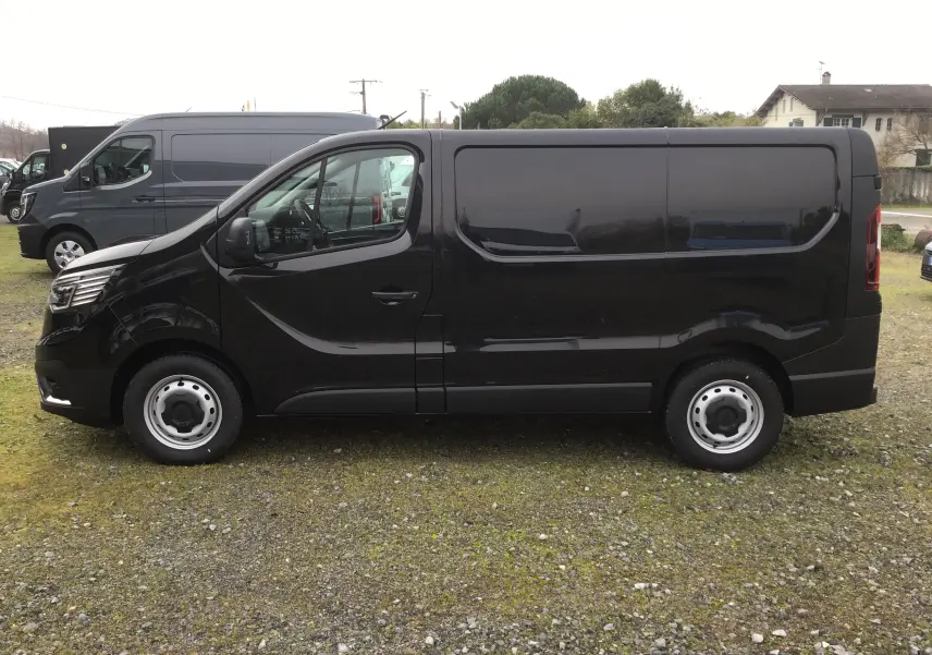 Vue de profil côté gauche d’un Renault Trafic Fourgon noir 2025 avec jantes acier et vitres teintées.