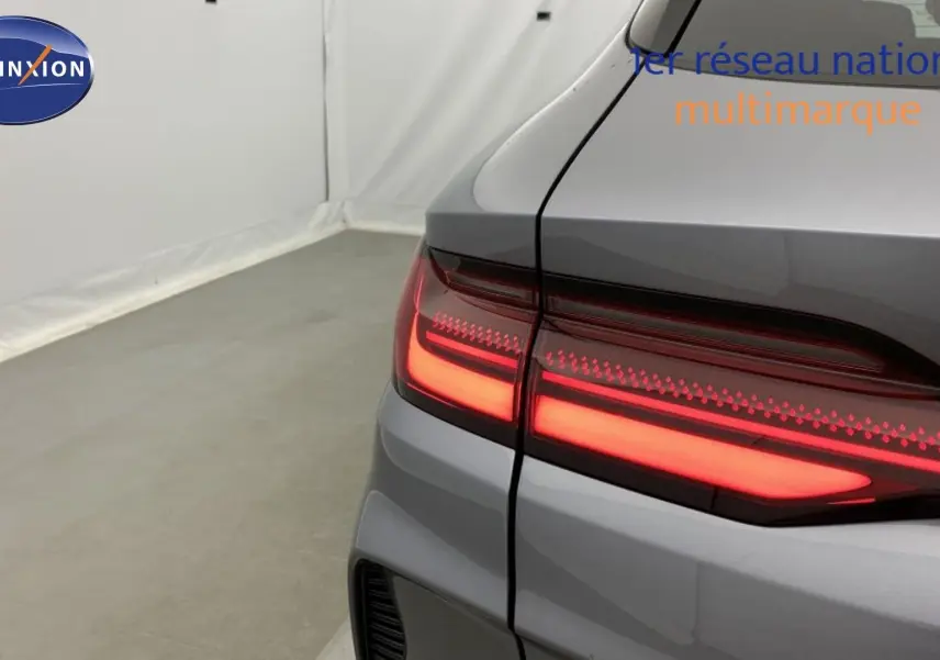 Vue arrière du coffre ouvert du BYD SEAL U Time Grey 2025 avec feux arrière LED allumés et deux sacs de rangement à l’intérieur.