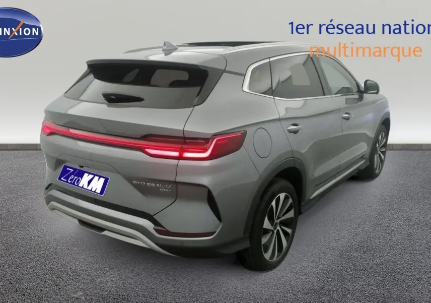 Vue 3/4 arrière droite du SUV BYD SEAL U gris Time Grey avec feux arrière LED allumés et jantes alliage bicolores.