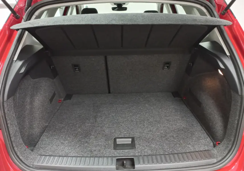 Coffre ouvert vu de l’arrière d’un SEAT Arona rouge Désir avec toit noir, montrant l’espace de chargement vide et la moquette grise.