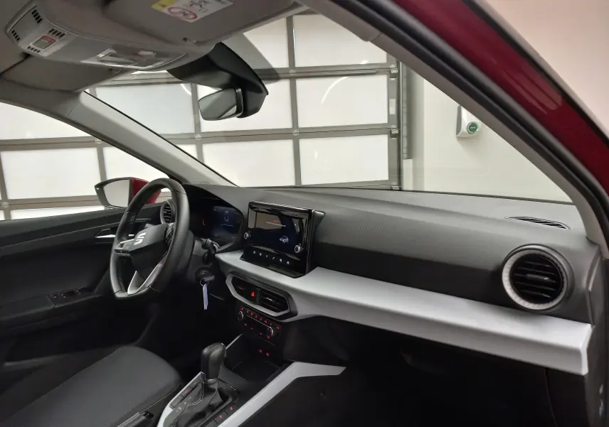 Vue intérieure côté conducteur du SEAT Arona rouge Désir avec tableau de bord moderne et écran tactile central.