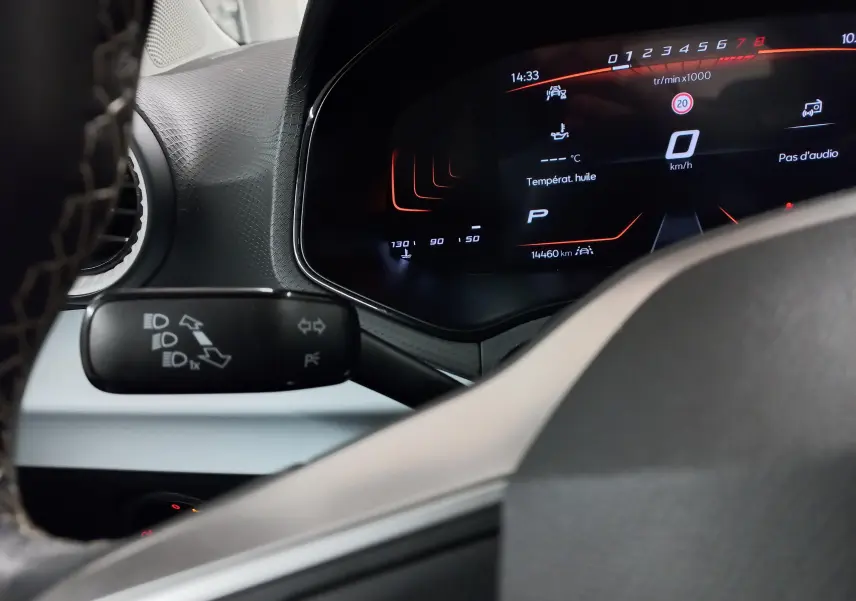 Vue rapprochée du tableau de bord numérique du SEAT Arona 2025, affichant la vitesse à zéro et les commandes des phares.