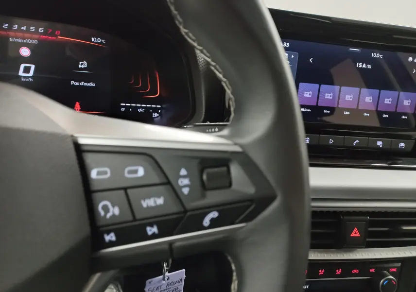 Vue intérieure rapprochée du tableau de bord et volant du SEAT Arona 2025 avec écran tactile et commandes au volant visibles.
