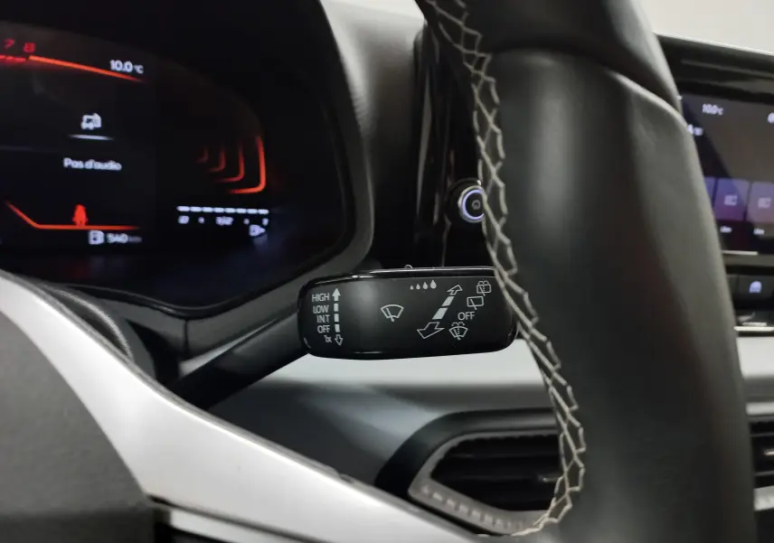 Gros plan sur le commodo d’essuie-glace côté droit du tableau de bord du SEAT Arona 2025, volant cuir noir.